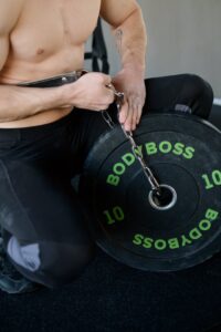 Athletic man setting up weights with chains for strength training indoors.